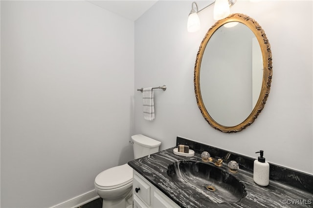 bathroom with vanity, toilet, and baseboards