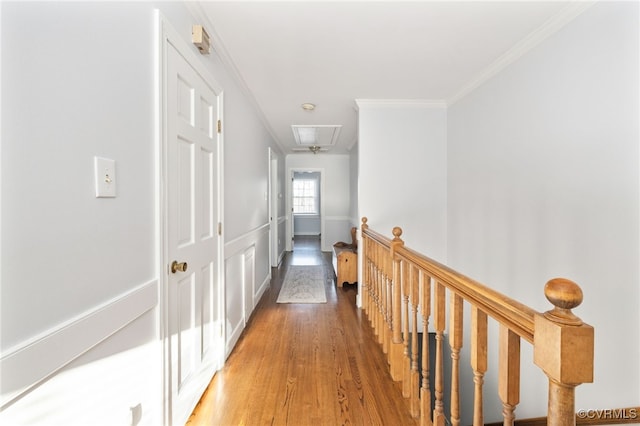 hall featuring light wood finished floors, attic access, ornamental molding, and an upstairs landing