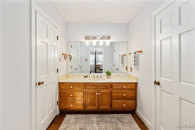 bathroom featuring baseboards, vanity, ensuite bath, and wood finished floors