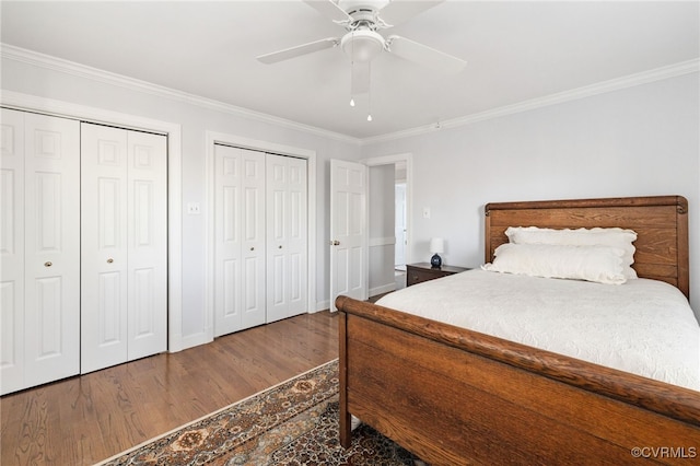 bedroom featuring crown molding, multiple closets, a ceiling fan, wood finished floors, and baseboards