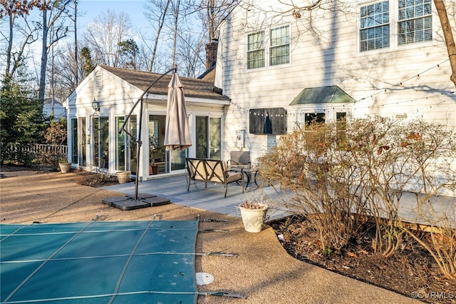 rear view of house with a patio area, a chimney, and a sunroom