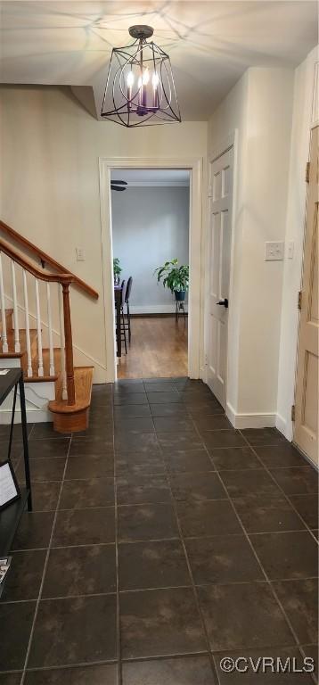 corridor with dark tile patterned flooring and a chandelier