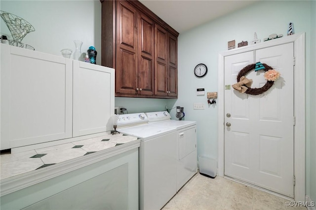 clothes washing area featuring light tile patterned flooring, cabinets, and washer and dryer