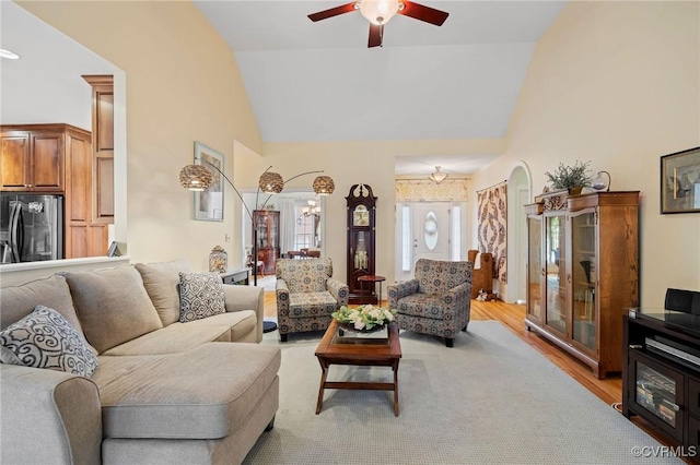 living room featuring light hardwood / wood-style flooring, high vaulted ceiling, and ceiling fan