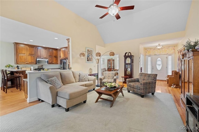 living room featuring ceiling fan, high vaulted ceiling, and light hardwood / wood-style floors