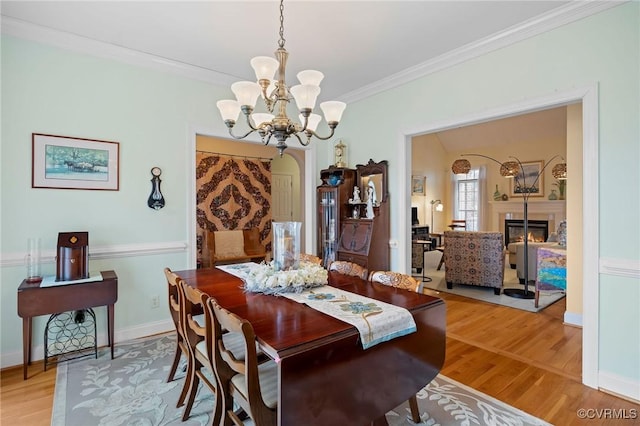 dining area with a notable chandelier, wood-type flooring, and ornamental molding