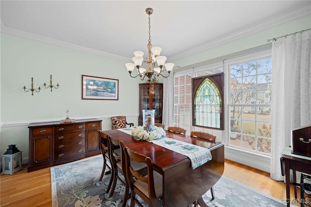 dining space with crown molding, a chandelier, a healthy amount of sunlight, and light wood-type flooring