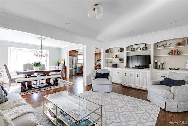 living room featuring an inviting chandelier, ornamental molding, dark hardwood / wood-style flooring, and built in features