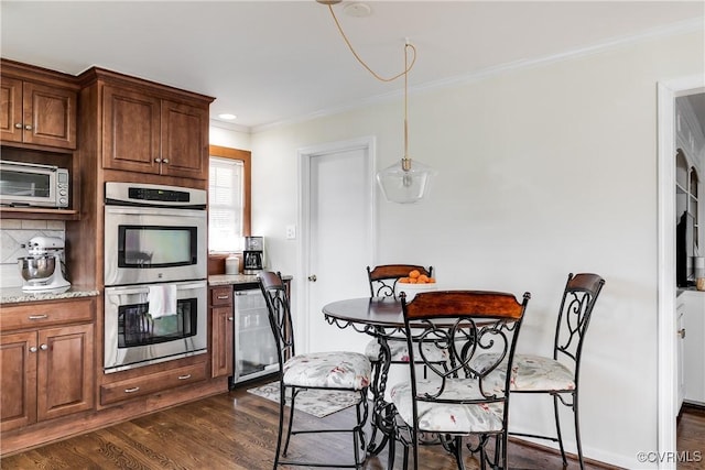 kitchen featuring dark wood-type flooring, backsplash, light stone counters, ornamental molding, and stainless steel double oven