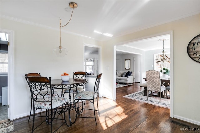 dining area with ornamental molding, dark hardwood / wood-style floors, and a notable chandelier