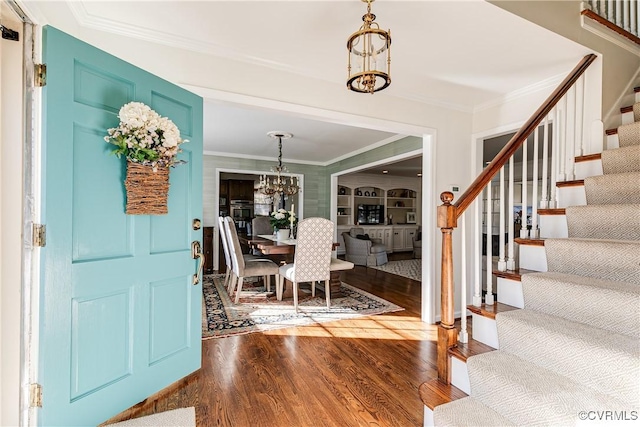 entrance foyer with wood-type flooring, ornamental molding, and a chandelier