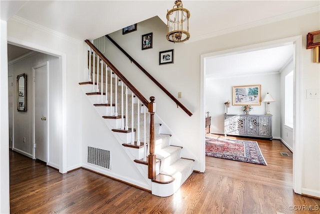 stairway featuring crown molding, hardwood / wood-style floors, and a notable chandelier