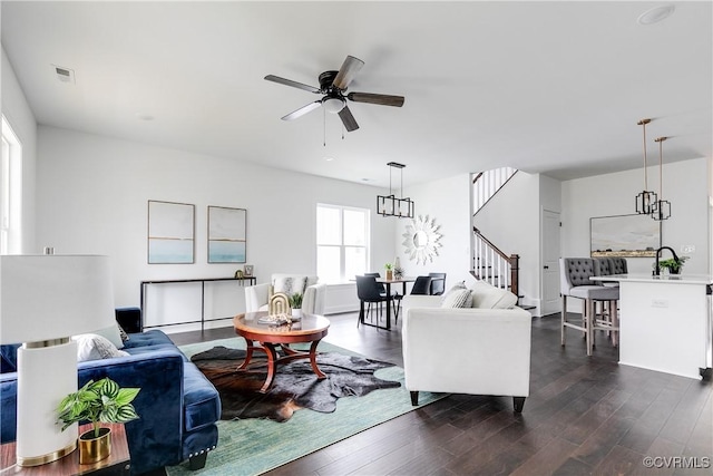 living room featuring sink, dark hardwood / wood-style flooring, and ceiling fan with notable chandelier