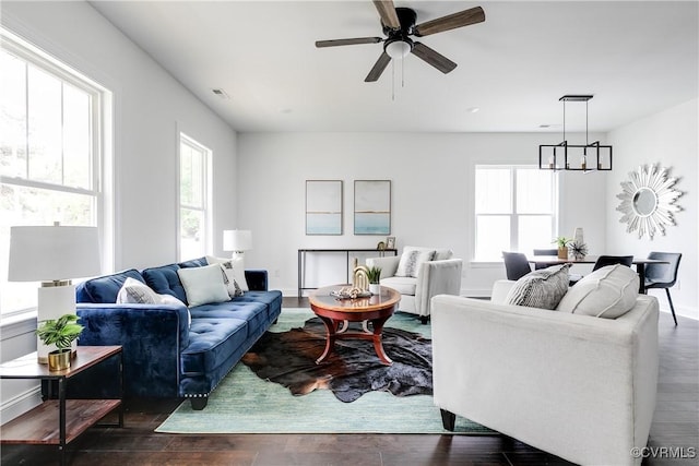 living room with dark wood-type flooring and ceiling fan with notable chandelier