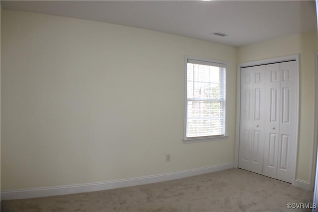 unfurnished bedroom featuring light colored carpet and a closet