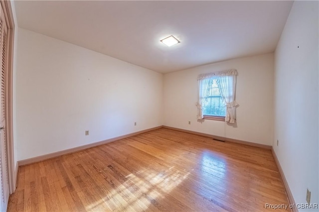 spare room with light wood-style flooring and baseboards