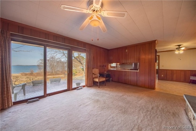 interior space with visible vents, a water view, a ceiling fan, ornamental molding, and light carpet