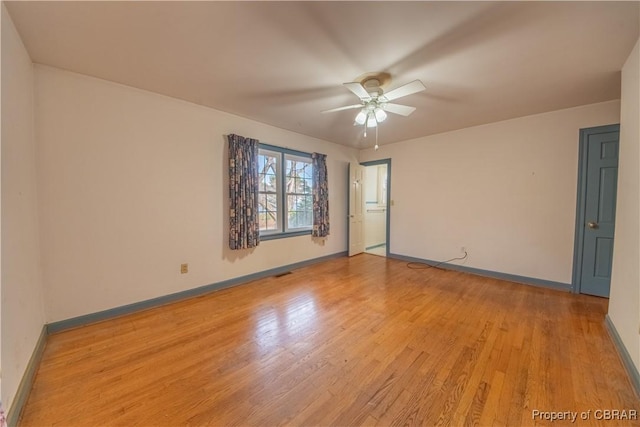 spare room with baseboards, ceiling fan, visible vents, and light wood finished floors