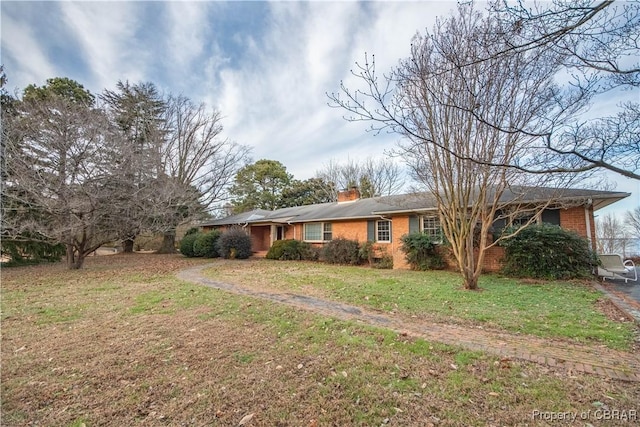 single story home with a chimney, a front lawn, and brick siding