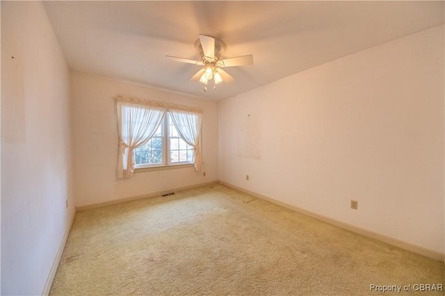 unfurnished room with baseboards, ceiling fan, visible vents, and light colored carpet