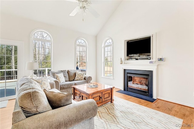 living room with ceiling fan, high vaulted ceiling, and light hardwood / wood-style floors