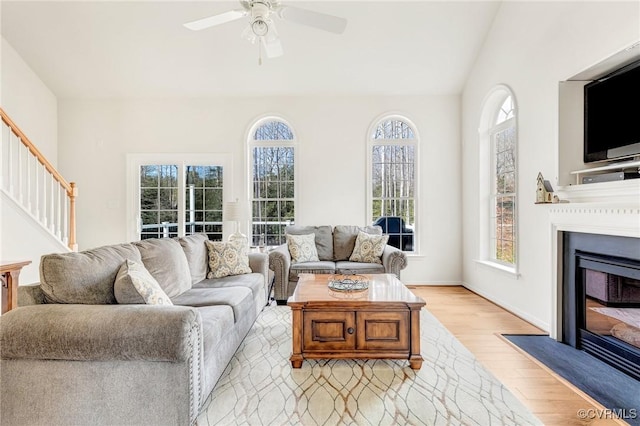 living room featuring light hardwood / wood-style flooring, plenty of natural light, ceiling fan, and vaulted ceiling