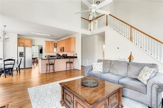 living room featuring light hardwood / wood-style floors, ceiling fan, and a high ceiling