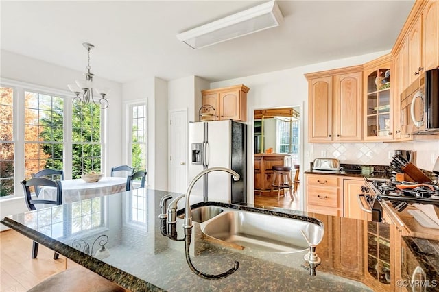 kitchen with pendant lighting, sink, dark stone counters, and appliances with stainless steel finishes