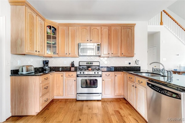 kitchen featuring light brown cabinetry, sink, stainless steel appliances, and dark stone counters