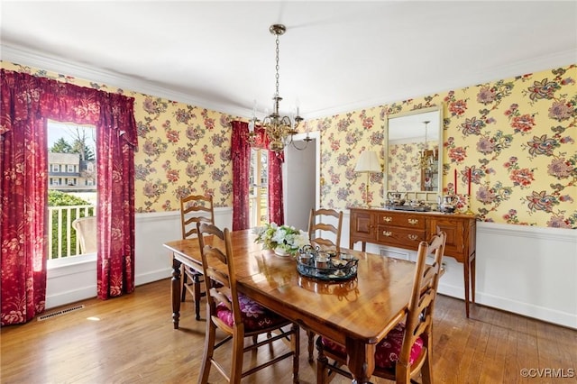 dining room featuring wainscoting, wood finished floors, and wallpapered walls