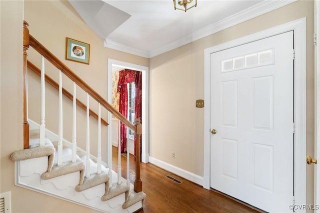 foyer featuring baseboards, visible vents, ornamental molding, wood finished floors, and stairs