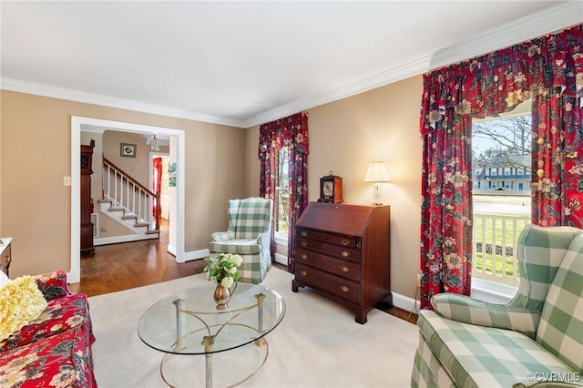 living area with baseboards, stairway, wood finished floors, and crown molding