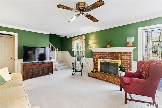 living area with a brick fireplace, carpet, stairs, and crown molding