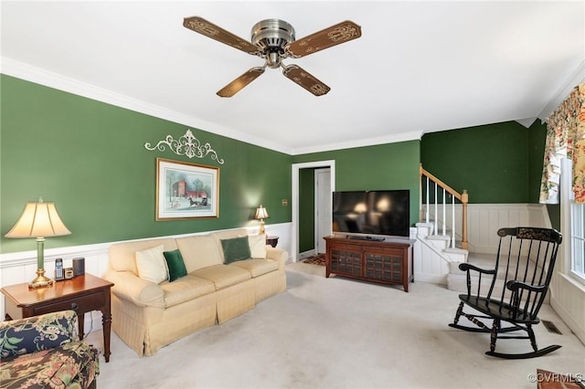 living area featuring carpet, wainscoting, crown molding, and stairway