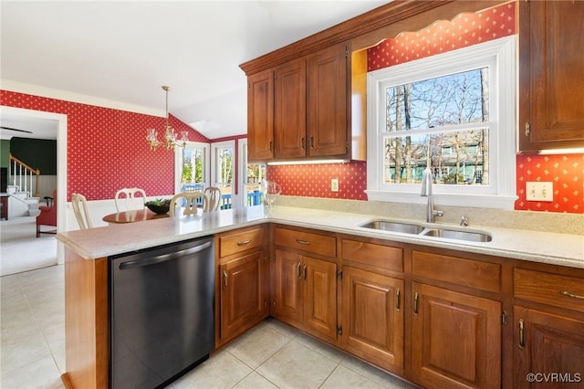 kitchen featuring a sink, light countertops, stainless steel dishwasher, brown cabinetry, and wallpapered walls