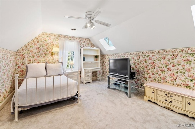 bedroom featuring vaulted ceiling with skylight, light colored carpet, visible vents, a ceiling fan, and wallpapered walls