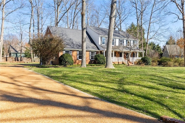 view of front facade with covered porch, brick siding, and a front yard