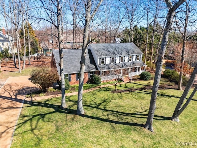 view of front of property with brick siding, a porch, and a front yard