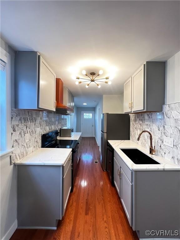 kitchen featuring wall chimney exhaust hood, sink, dark hardwood / wood-style flooring, black range with electric cooktop, and decorative backsplash