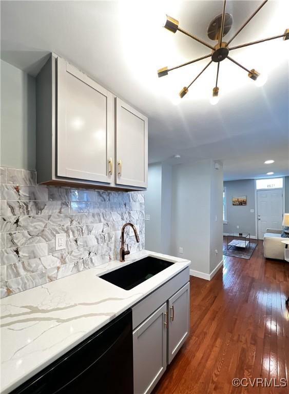 kitchen featuring sink, gray cabinets, dark hardwood / wood-style floors, light stone counters, and decorative backsplash