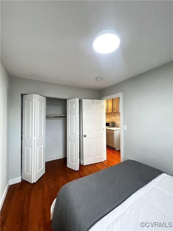 bedroom with dark hardwood / wood-style floors and a closet