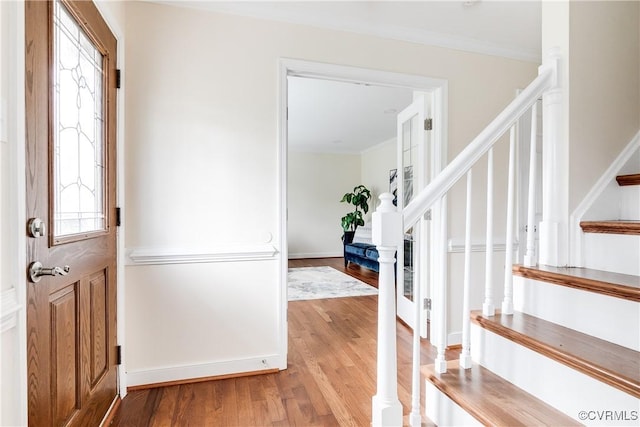 foyer entrance with stairs, light wood-type flooring, baseboards, and crown molding