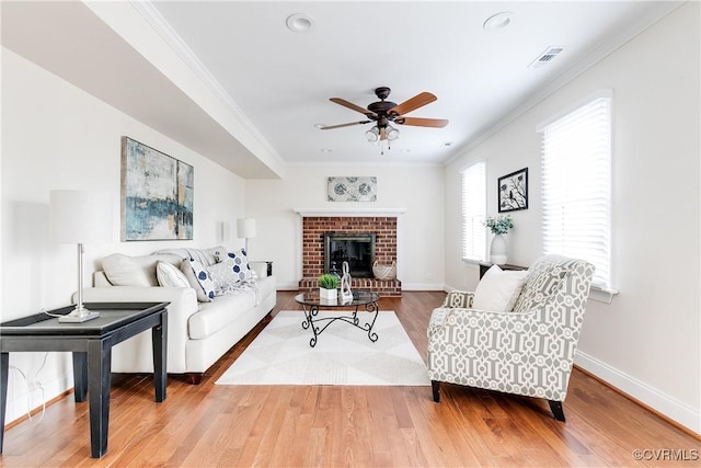 living area with ceiling fan, wood finished floors, visible vents, baseboards, and ornamental molding