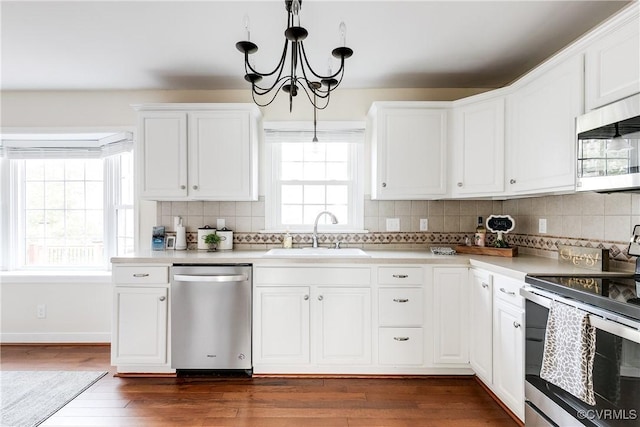 kitchen featuring a sink, white cabinetry, light countertops, appliances with stainless steel finishes, and decorative light fixtures