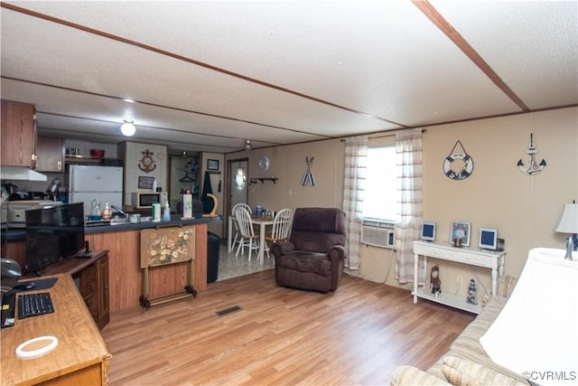 living room featuring cooling unit, a textured ceiling, and light wood-type flooring