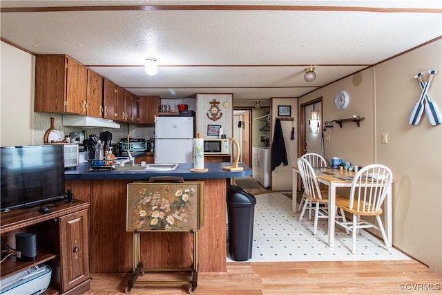 kitchen featuring sink, white appliances, light hardwood / wood-style floors, and a textured ceiling