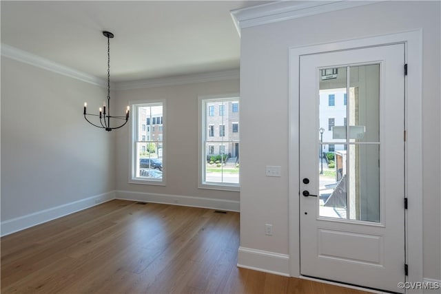 entryway featuring crown molding, wood-type flooring, and a chandelier