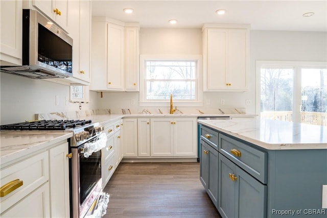 kitchen with appliances with stainless steel finishes, a healthy amount of sunlight, gray cabinetry, and white cabinets