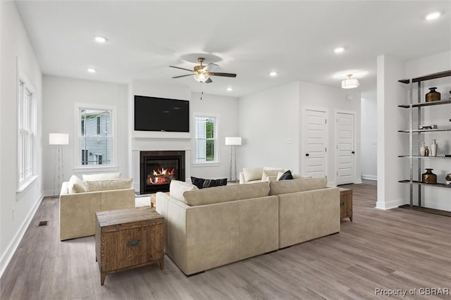 8280 Mobjack Ln, Hayes, VA 23072 - living area featuring a glass covered fireplace, light wood-style floors, a ceiling fan, and baseboards
