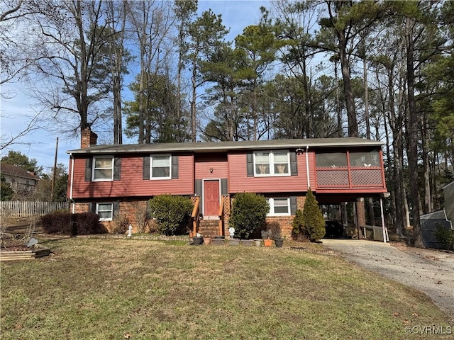 raised ranch with brick siding, driveway, a carport, a chimney, and a front yard